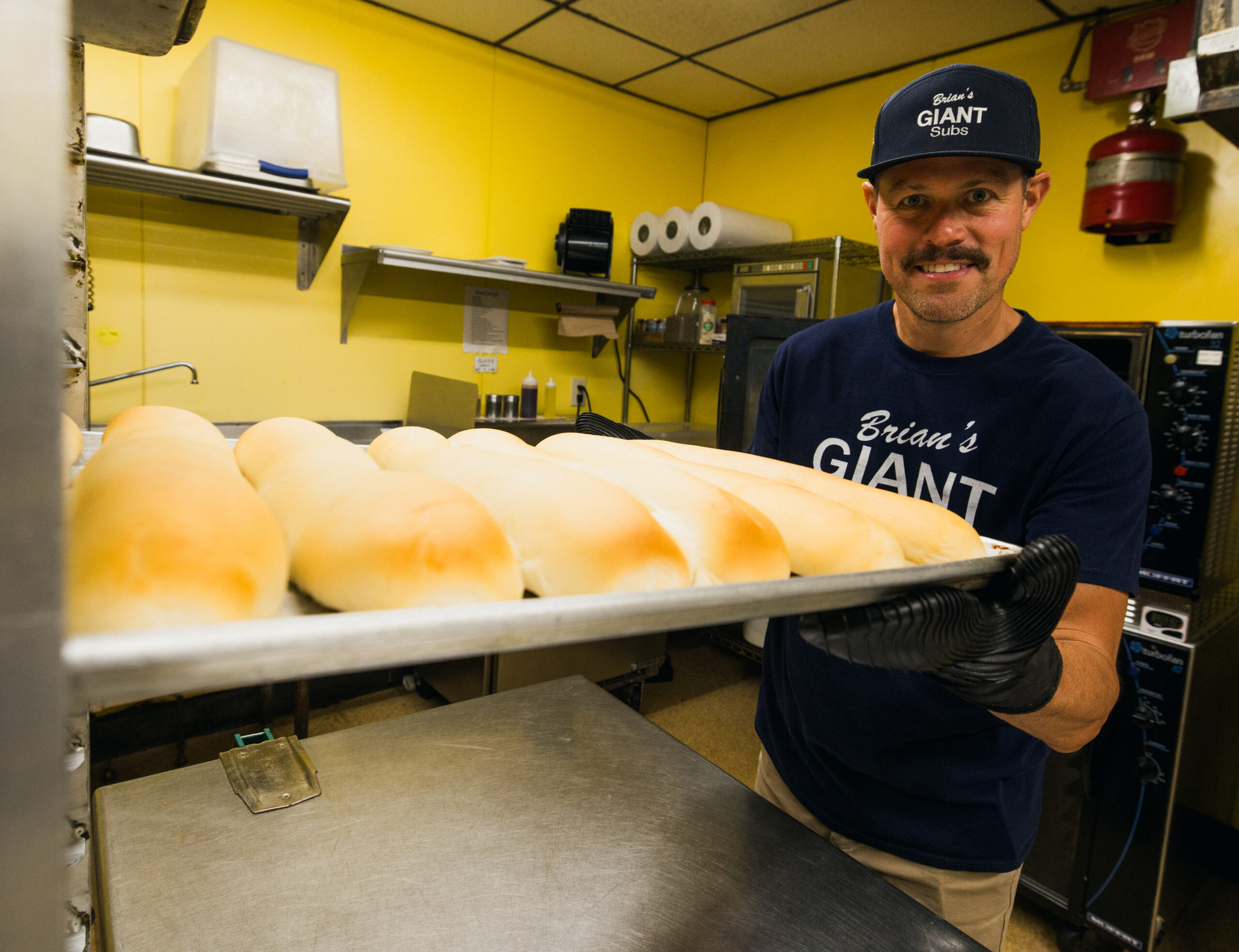 Brian's owner Brad Meeks pulling fresh baked bread out of the oven to prepare subs.
