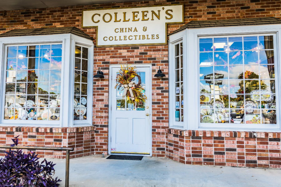 The exterior of Colleen's China showcasing the tableware display in two windowns flanking the door adorned with a colorful wreath.