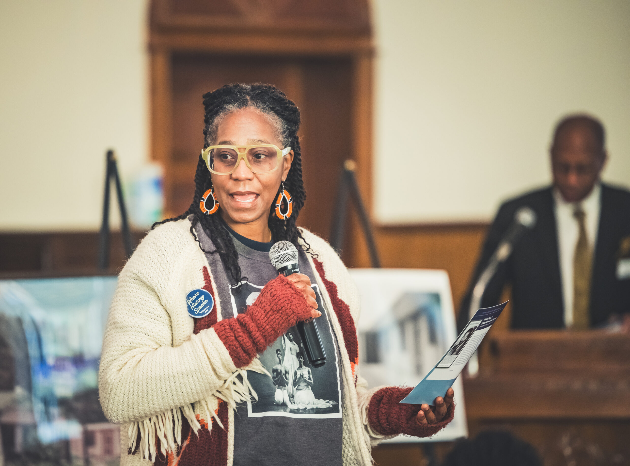 Woman speaks into a microphone, holding a card with her lines during One Day: Dublin's Civil Rights Experience